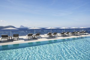 großer und moderner infinity pool mit blick auf das mittelmeer und bequemen sonnenliegen im 7 pines hotel auf ibiza