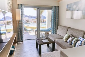 wohnbereich des wunderschönen 7 pines hotel mit warmen holzmöbeln und blautönen direkt an der terrasse mit zugang zum pool