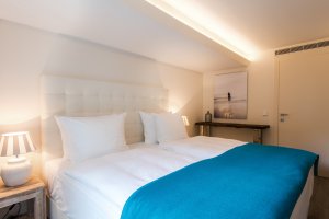 helles und großes bett mit türkisfarbenen details im 7 pines hotel auf ibiza