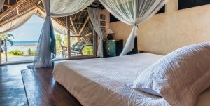 großes himmelbett im schlafzimmer einer garden ville des Alfajiri Villas Hotel in Kenia mit blick auf den ozean