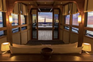 großes doppelbett mit blick auf das offene meer und das deck des luxusschiffes von aman mit einer gemütlichen lounge zum beobachten der sterne