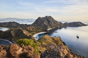 blick von einem berg auf die felsige küste von indonesien und die bucht in der das luxusschiff amandira auf dem blauen ozean liegt