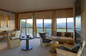 großer Wohnraum mit vielen tiefen Fenstern und Blick in die Natur einer Spring Gulch Suite im Aman Amangani Luxusresort Wyoming USA