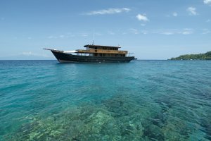 das luxusschiff aus holz der exklusiven kette aman von der seite auf glasklarem wasser vor indonesien