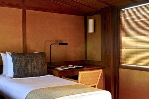 einzelbett in einer dreibett kabine auf dem luxusschiff amanikan von aman resorts mit holzwänden und gemütlicher einrichtung