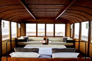 gemütlicher wohnraum vor dem großen doppelbett der master cabin auf dem luxusschiff amanikan von aman vor indonesien für einen romantischen traumurlaub