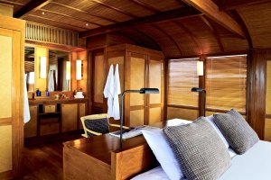 offenes badezimmer direkt hinter dem großen doppelbett der luxuriösen master kabine auf dem holzschiff amanikan vor indonesien mit viel holz gemütlich eingerichtet