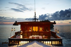 sonnendeck auf dem deck des luxusschiffes amanikan mit romantischer beleuchtung bei sonnenuntergang und abenddämmerung auf dem ozean vor indonesien