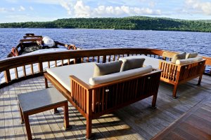 blick auf das deck des luxus schiffes amanikan mit zwei doppelliegen aus holz und gemütlichen weißen polstern unter strahlend blauem himmel laden zum sonnen und relaxen ein
