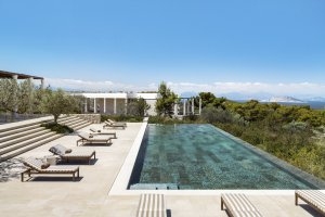 Blick auf die gesammte Terrasse einer 5 Zimmer Villa im Amanzoe mit großem Pool der blau-grün schimmert und einen schönen Kontrast zum strahlen blauen Himmel gibt