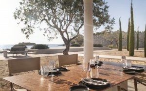 Luxusresort Griechenland Gedeckter Tisch im Amanzoe Beach Club inmitten von Zypressen am Strand mit Blick aufs Meer