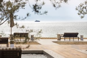 Blick aufs Meer vom Beach Club des Amanzoe aus mit hellem Holzdeck und Liegen