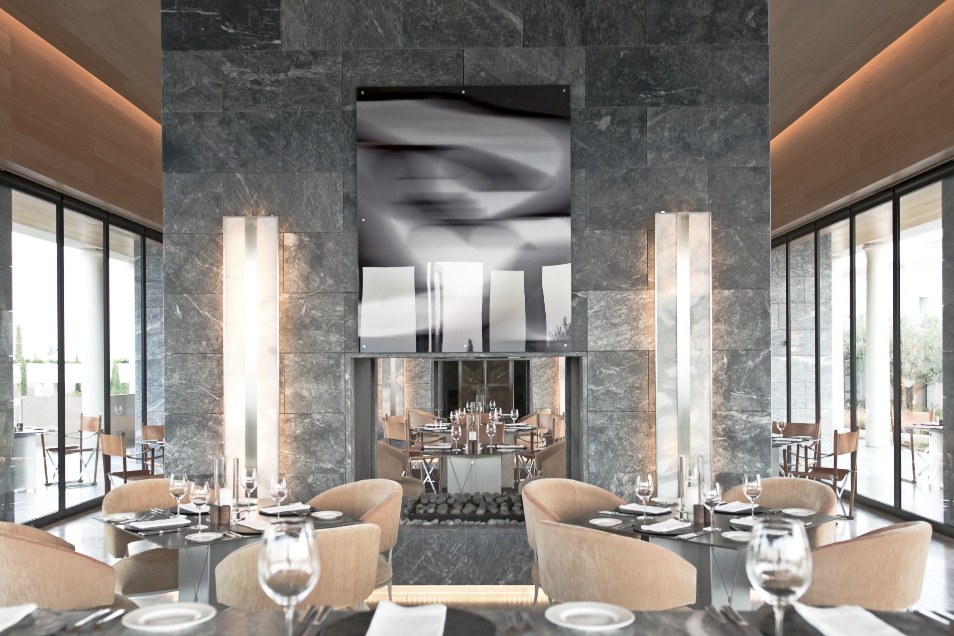 Restaurant des Amanzoe mit viel Stein und Glas und gemütlichen Essstühlen in hellen Stoffen