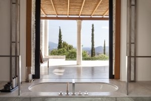 Badezimmer eines Pavilion im Amanzoe mit Blick nach draußen auf die Zypressen und die Landschaft
