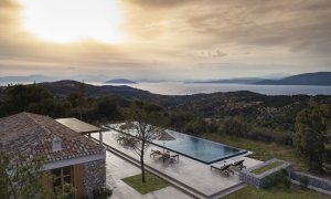 Herrlicher Blick bei Sonnenuntergang auf die Villa 31 des Amanzoe in Griechenland mit großem Pool vor der Villa Luxusresort Griechenland