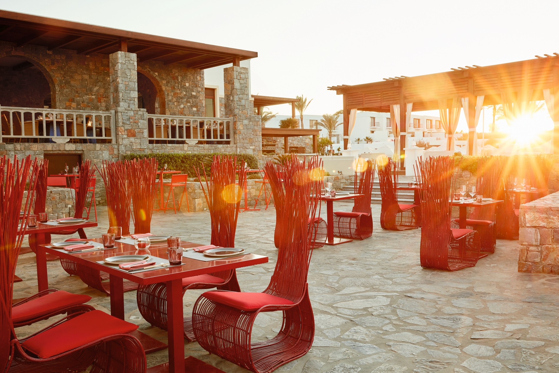 asiatisches restaurant mit exklusiver einrichtung auf der terrasse im luxushotel amirandes mit roten hohen sesseln bei sonnenuntergang
