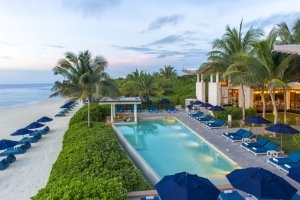 Luxusurlaub Mexiko im Banyan Tree Mayakoba Blick auf den Pool am Strand mit bequemen Sonnenliegen, Schrimen und umgeben von Palmen