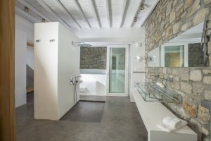 großes modernes badezimmer der luxus villa big blue beach auf mykonos mit steinwänden und geradliniger ausstattung mit großer dusche