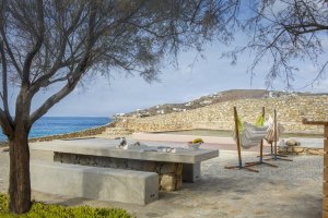 freizeitbereich der privaten villa big blue beach villa auf mykonos mit hängematte und pool unter dem schatten eines alten olivenbaum direkt am meer