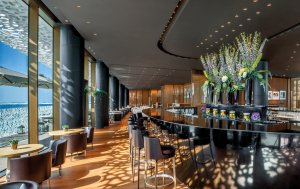moderne und große bar mit heller fensterfront und blick auf das meer im luxushotel bulgari dubai