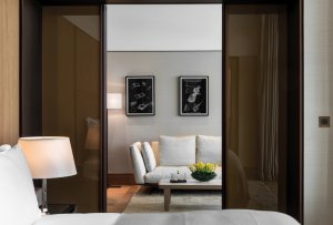 blick vom schlafzimmer der junior suite im bulgari hotel dubai aus zum wohnbereich mit hellen möbeln und viel platz