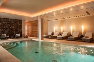 edler und schöner pool im spa bereich des luxus 5 sterne hotels castell son clarett auf mallorca mit liegen und hellen farbtönen direkt am pool mit runder treppe in der ecke.