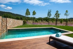 schlichter privater pool in der Pool Suite im luxus hotel castell son clarett auf mallorca umgeben von holzplanken und blick in den wunderschönen grünen garten