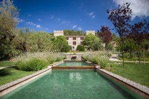 wunderschönes Luxushotel Castell Son Claret mit blick aus dem Garten über das wasserfall artige wasser das den garten durchkreuzt unter strahlend blauem himmel auf mallorca
