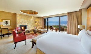 helle deluxe suite in hellen farben mit offenen kamin und blick auf die natur aus den großen fenstern wunderschönes Golfhotel Südafrika Conrad Pezula inmitten saftig grüner natur gelegen.