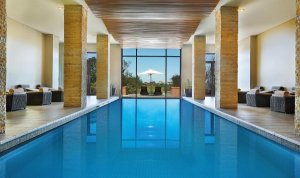 hellblauer Spa Pool mit blick ins freie des wunderschönes Golfhotel Südafrika Conrad Pezula inmitten saftig grüner natur gelegen.