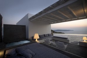 gemütliche und moderne lounge außen mit sitzecke und eigenem jacuzzi bei sonnenuntergang in der privaten villa erosantorini