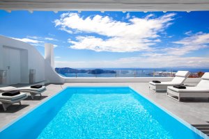 pool mit sonnenliegen und meerblick in der privaten villa erossea auf santorini unter strahlend blauem himmel für einen individuellen luxusurlaub