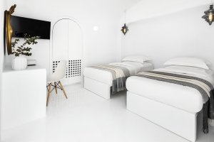sehr helles schlafzimmer der privaten luxus villa erossea auf santorini mit zwei getrennten einzelbetten und moderner weißer einrichtung