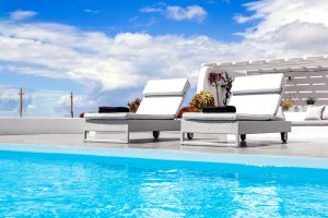 sonnenliegen am pool der privaten luxus villa erossea auf santorini mit modernen möbeln auf der großen terrasse unter blauem himmel