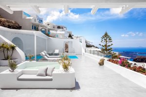 großzügige terrasse mit meerblick und privatem pool mit sonnenliegen in der luxuriösen privaten villa erossea auf santorini bei strahlendem sonnenschhein