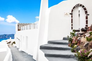treppe zum eingang der privaten luxus villa erossea im typisch griechischem design unter strahlend blauem himmel und blick zum meer laden zum individuellen entspannen ein