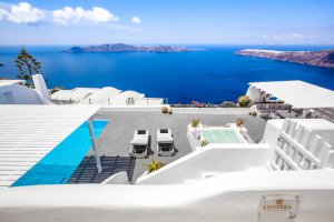 blick von oben auf die moderne und luxuriöse terrasse der privaten villa erossea auf santorini mit blick auf das drunkelblaue meer und die küste