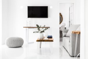moderner tv an der wand des hellen wohnzimmer im strahlenden weiß und minimalistischer einrichtung im wohnraum der modernen luxus villa erossea auf santorini