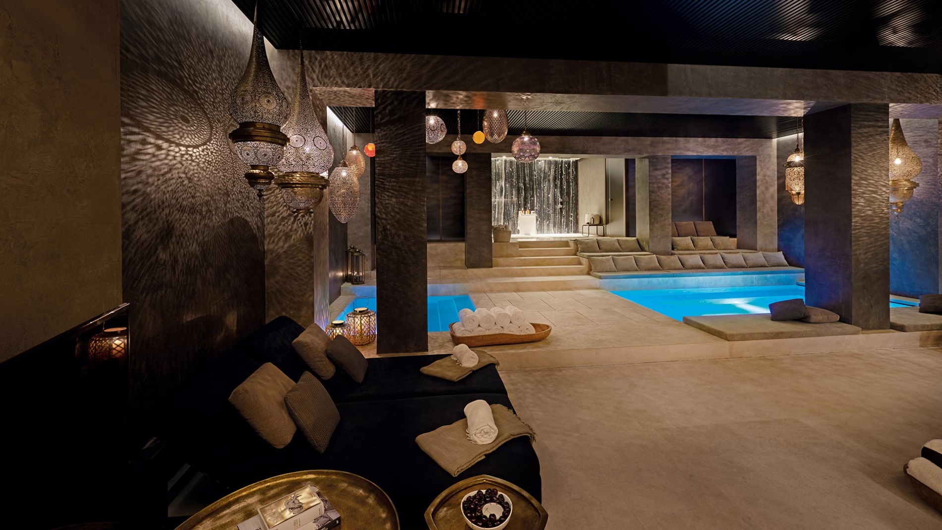 blick in den warm gestalteten spa bereich des ferradura privat resort mit dunklen wänden und hellen erdtönen umgeben von gemütlichen sitzecken