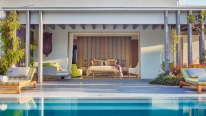 blick ueber den privaten pool der villa auf ibiza in das große schlafzimmer der luxus villa isla sa ferradura mit großer terrasse und sonnenliegen fuer einen exklusiven traumurlaub