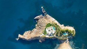blick von oben auf die privatinsel ferradura mit wohngebäude und privatem infinity pool umringt von dunkelblauem wasser des mittelmeers