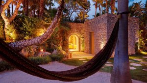blick in den idylischen garten der privatinsel ferradura umringt von palmen und alten steinmauern mit hängematte inmitten des gartens über einem sandbeet schwebend
