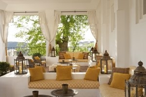 Indien Lounge bei Tag mit Blick nach draußen und den gemütlichen gelben Postern auf gemauerten Sitzecken in der Finca Cortesin an der Costa del Sol