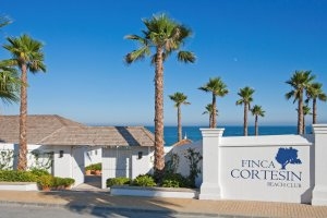 Eingang zum Finca Cortesin Beach Club mit mediterranen Palmen und blick aufs strahlend blaue Mittelmeer direkt am Strand 