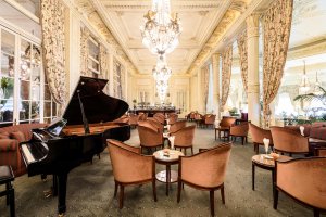 historische bar imperial mit klavier flügel inmitten des raums und gemütlichen sesseln in warmen farben im hotel du palais