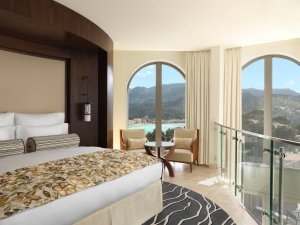 einmalig traumhafte Lighthouse Suite mit Rundumblick auf die malerische Küste und großem Bett umgeben von großen Fenstern im Luxushotel Mallorca Jumeirah Port Soller Hotel & Spa