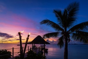 Abenddämmerung im Likuliku Lagoon Resort mit blau bis lila schimmernder Südsee unter Palmen garantiert einen romantischen Luxusurlaub