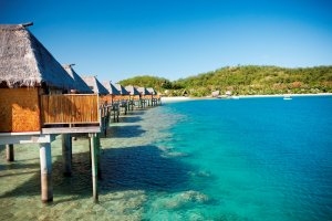 Blick über das Riff vor dem Likuliku Lagoon Resort mit den Over Water Bures direkt auf dem Wasser gebaut für einen Luxusurlaub oberster Klasse im türkisfarbenen Südsee Wasser