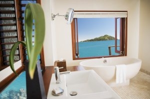 helles Badezimmer eines Overwater Zimmers mit Blick aus dem Fenster auf die türkisfarbene Südsee mit großer Badewanne direkt vor dem Fenster verspricht einen Luxusurlaub oberster Klasse im Likuliku Lagoon Resort auf Fiji