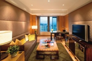 Wohnbereich der Executive Suite im Mandarin Oriental Tokyo mit gemütlichem Sofa und großem Flachbild-TV